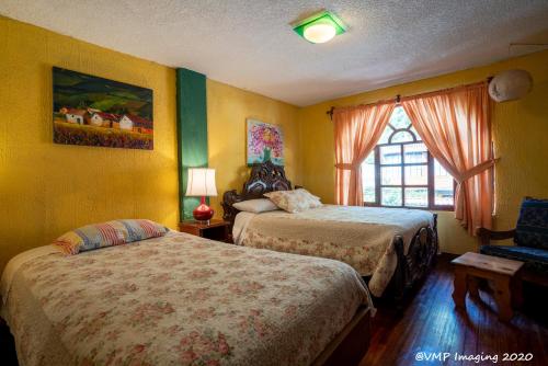a hotel room with two beds and a window at La Posada Del Arte in Baños