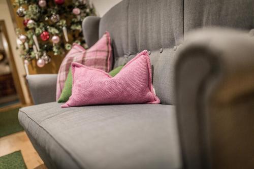 a gray couch with two pink pillows and a christmas tree at Restaurant Gästehaus Wiesenheim in Uderns