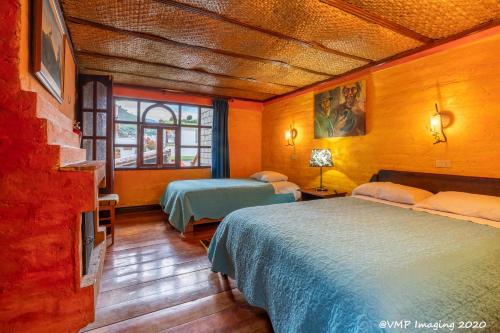 a hotel room with two beds and a tv at La Posada Del Arte in Baños