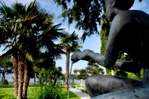 a statue of a man sitting next to palm trees at Hotel Marko in Portorož