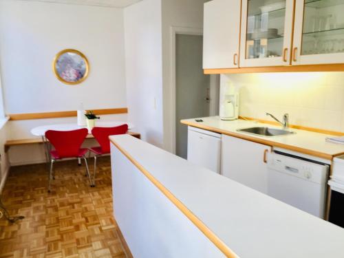 uma cozinha com armários brancos e uma mesa e cadeiras em City Hotel Apartments em Odense