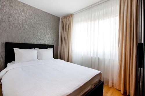 a bedroom with a large white bed and a window at Arcul de Triumf Residence in Bucharest