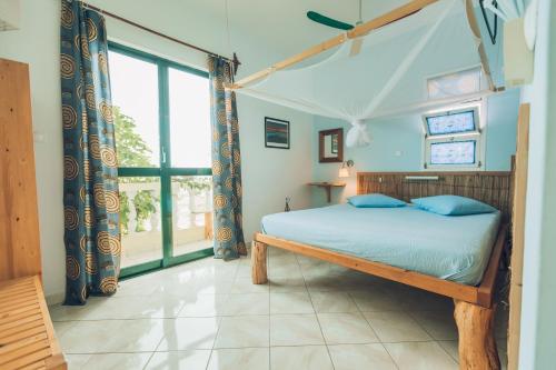 um quarto com uma cama e uma grande janela em Casa Strela B&B Tarrafal em Tarrafal