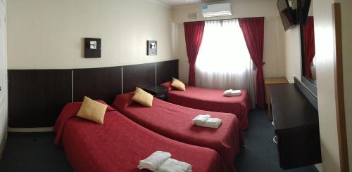 2 camas en una habitación de hotel con sábanas rojas en Gran Hotel Monaco en Mar del Plata