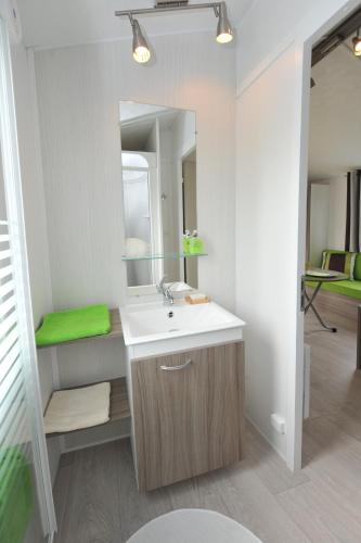une salle de bain avec un lavabo et un miroir dans l'établissement Camping Les Brillas, à Les Moutiers