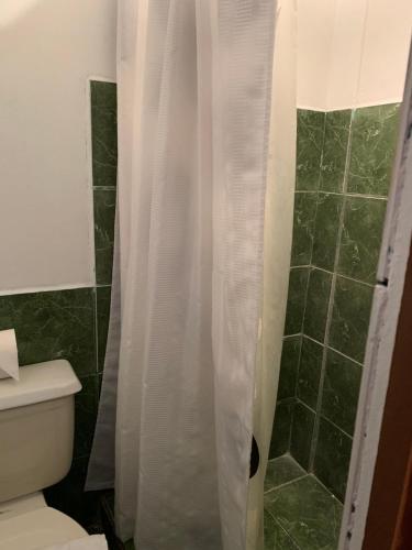 a bathroom with a shower with a white shower curtain at Hotel Don Robert in Puntarenas