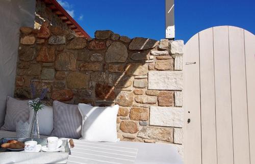 a room with a stone wall and a table with pillows at Lithea Villas and Studios by the Sea in Aghios Petros Alonissos