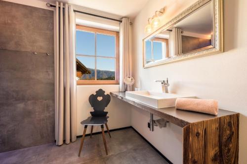 a bathroom with a sink and a mirror and a chair at oma luisa - schlosserhaus 31 in Tesimo