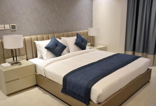 a bedroom with a large bed with blue and white pillows at The Lodge Suites in Manama