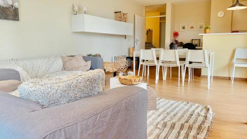 a living room with a couch and a table and chairs at Ruim, lichtrijk appartement met groot terras uitstekend gelegen in De Panne in De Panne