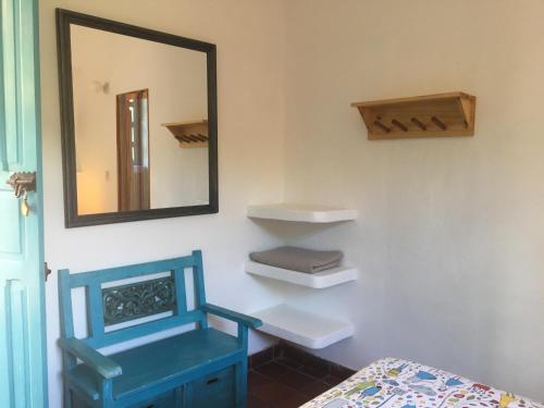 Cette chambre comprend un miroir, une chaise bleue et un lit. dans l'établissement Quinta Sans-Soucis, à Choachí