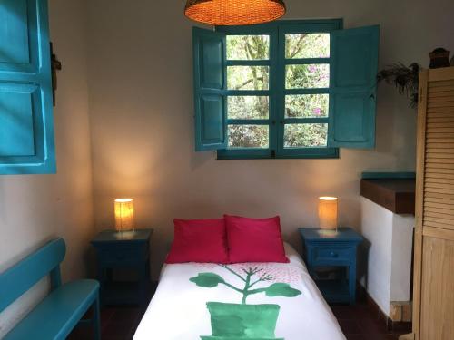 a bedroom with a bed with red pillows and a window at Quinta Sans-Soucis in Choachí
