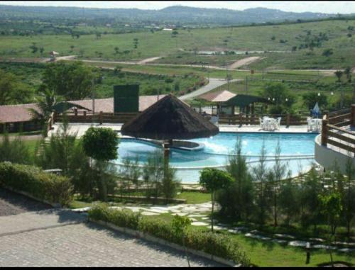 a large swimming pool with a thatch roof at Flat no Condomínio Monte Castelo em Gravatá in Gravatá