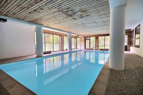a large swimming pool with blue water in a building at L'Enchalpe, Grand et lumineux studio avec coin montagne 5 personnes, 60m des pistes, PISCINE COUVERTE, WIFI, grand balcon expo EST, DRAPS NON COMPRIS in Saint-Jean-dʼAulps