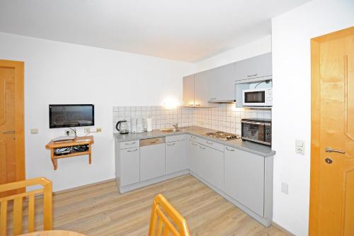 a kitchen with white cabinets and a counter top at Glemmy Appartements inkl Sommercard in Viehhofen