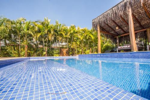 a swimming pool with a resort with palm trees at Pousada Vila Tamarindo Eco Lodge in Florianópolis