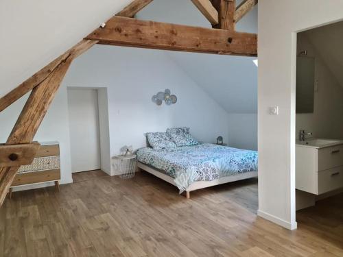 a bedroom with a bed and a wooden floor at Gîte Le Lijaly in Bournezeau