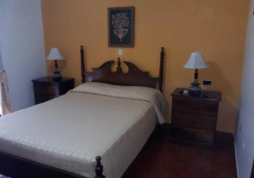 a bedroom with a bed and two night stands with lamps at Hotel Acropolis Maya in Copan Ruinas