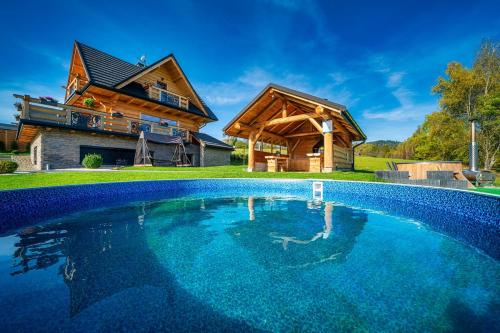 a large pool in front of a log house at Domek w górach DeLuxe sauna,jacuzzi,basen,hot tub-Nowy Targ blisko Białka ,Zakopane in Nowy Targ