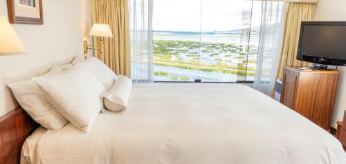 a bedroom with a white bed with a large window at GHL Hotel Lago Titicaca in Puno