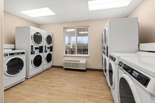 a laundry room with three washer and dryers at Candlewood Suites Sumner Puyallup Area by IHG in Sumner