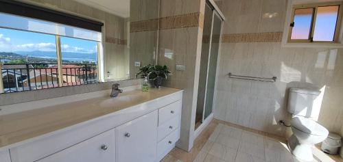 a bathroom with a sink and a toilet and a window at Shellharbour. Ocean, lake and mountain view in Shellharbour