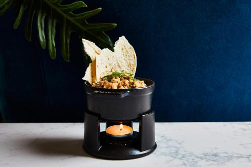 a candle in a container with some food in it at Kimpton Hotel Fontenot by IHG in New Orleans
