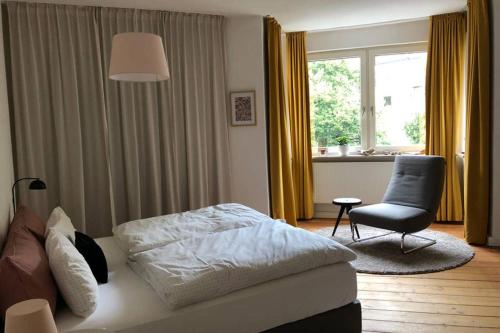 1 dormitorio con 1 cama, 1 silla y 1 ventana en Charmant Leben im Textilviertel - stilvolle Wohnung - zentral und ruhig, en Augsburg