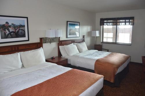 a hotel room with two beds and a window at Roosevelt Inn & Suites in Watford City