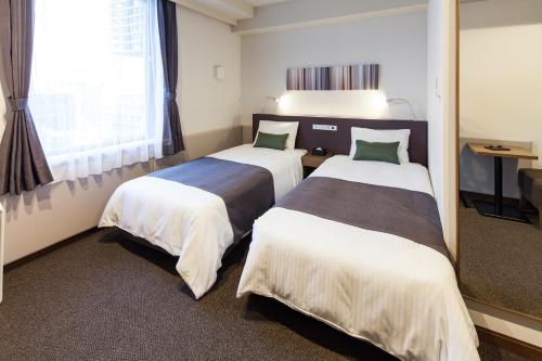a hotel room with two beds and a window at Y's HOTEL Hanshin Amagasaki Ekimae in Amagasaki