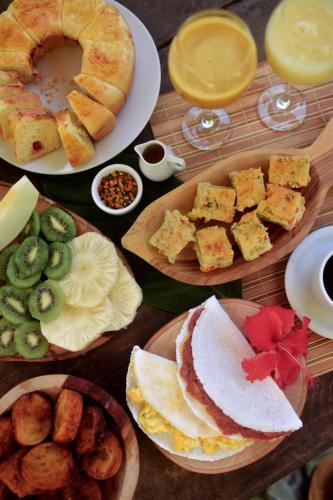 une table avec des assiettes de nourriture et des desserts dans l'établissement Vila das Ondas Caraíva, à Caraíva