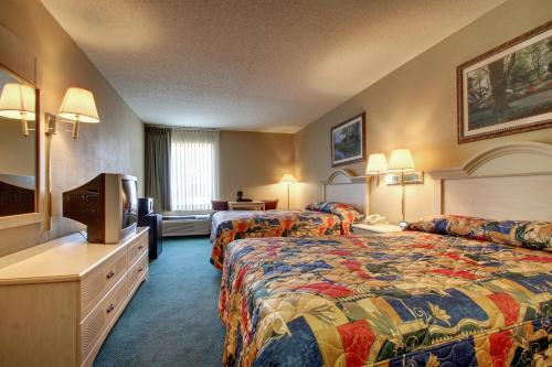 um quarto de hotel com duas camas e uma televisão de ecrã plano em Key West Inn - Baxley em Baxley