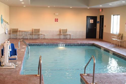 a pool in a hotel room with chairs and tables at Holiday Inn Express Pratt, an IHG Hotel in Pratt