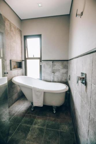 a large white tub in a bathroom with a window at Villa Amistà Campos do Jordão in Campos do Jordão