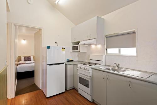 a white kitchen with a sink and a refrigerator at Discovery Parks - Lake Hume, Victoria in Bonegilla