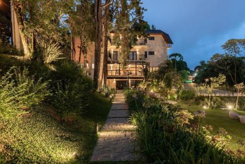 a house with a walkway in front of a yard at Villa Amistà Campos do Jordão in Campos do Jordão