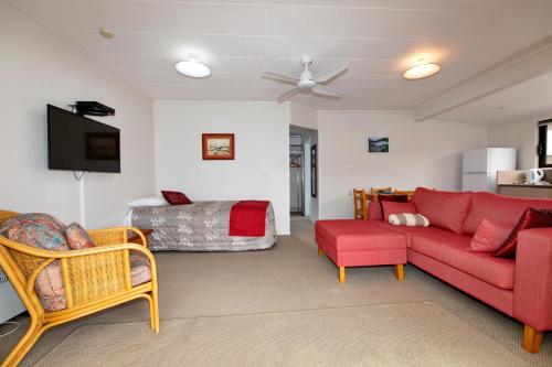 a living room with a red couch and a bed at Blue Marlin Apartments in Whitianga