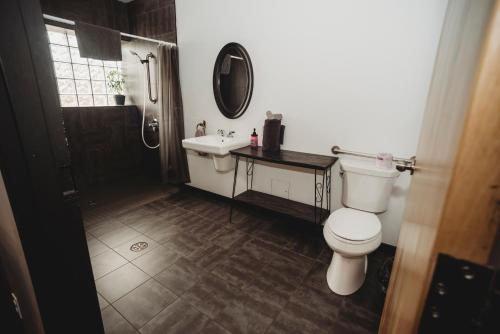 a bathroom with a toilet and a sink and a mirror at The Haven Hostel in Thunder Bay