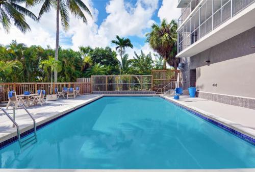 a swimming pool with palm trees and a building at Motel 6-Cutler Bay, FL in Cutler Bay