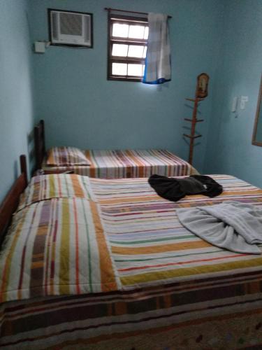 a bed with a striped comforter in a bedroom at APARTAMENTO SIMPLES E ACONCHEGANTE in Paraty