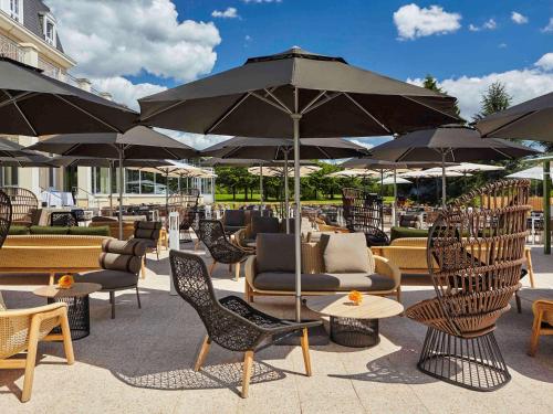 a patio with chairs and tables and umbrellas at Mercure Chantilly Resort & Conventions in Chantilly