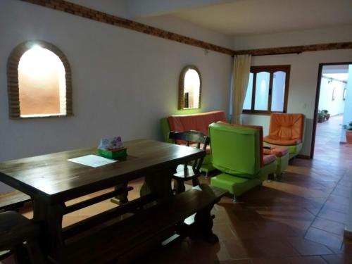 a living room with a wooden table and green chairs at Apartahotel La Gran Familia in Villa de Leyva