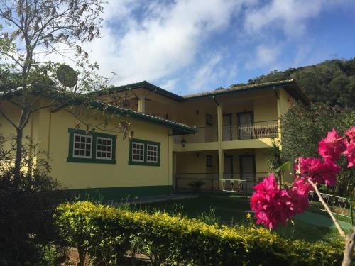 a yellow house with pink flowers in front of it at Pousada Primavera in São Luiz do Paraitinga