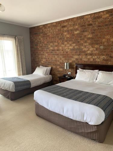a bedroom with two beds and a brick wall at Federation Motel Resort - Corowa in Corowa