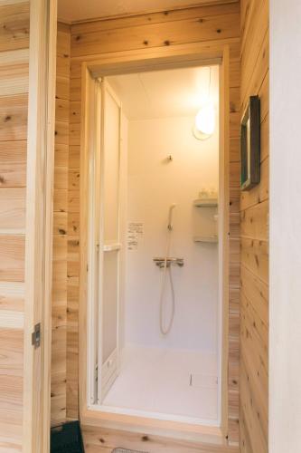 a bathroom with a shower in a wooden wall at Ise Guest House Kazami in Ise