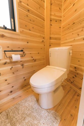 a bathroom with a toilet in a wooden wall at Ise Guest House Kazami in Ise