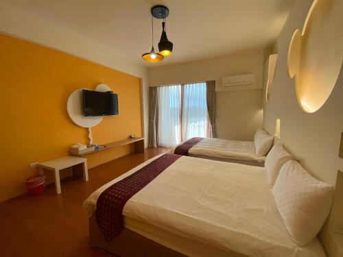a hotel room with two beds and a tv at 樂活小築民宿Lohas Taitung B&B in Taitung City