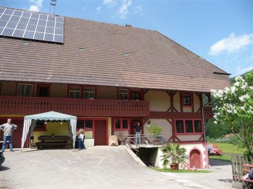 a large red building with a solar roof with people standing outside at Wäldebauernhof in Gutach