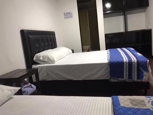a room with two beds and a table at Hostal El Eden Manizales in Manizales