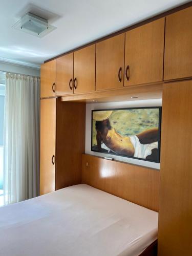 Un dormitorio con una cama y un cuadro en la pared. en Apartamento Aconchegante Beira Mar em Itapema - Santa Catarina, en Itapema